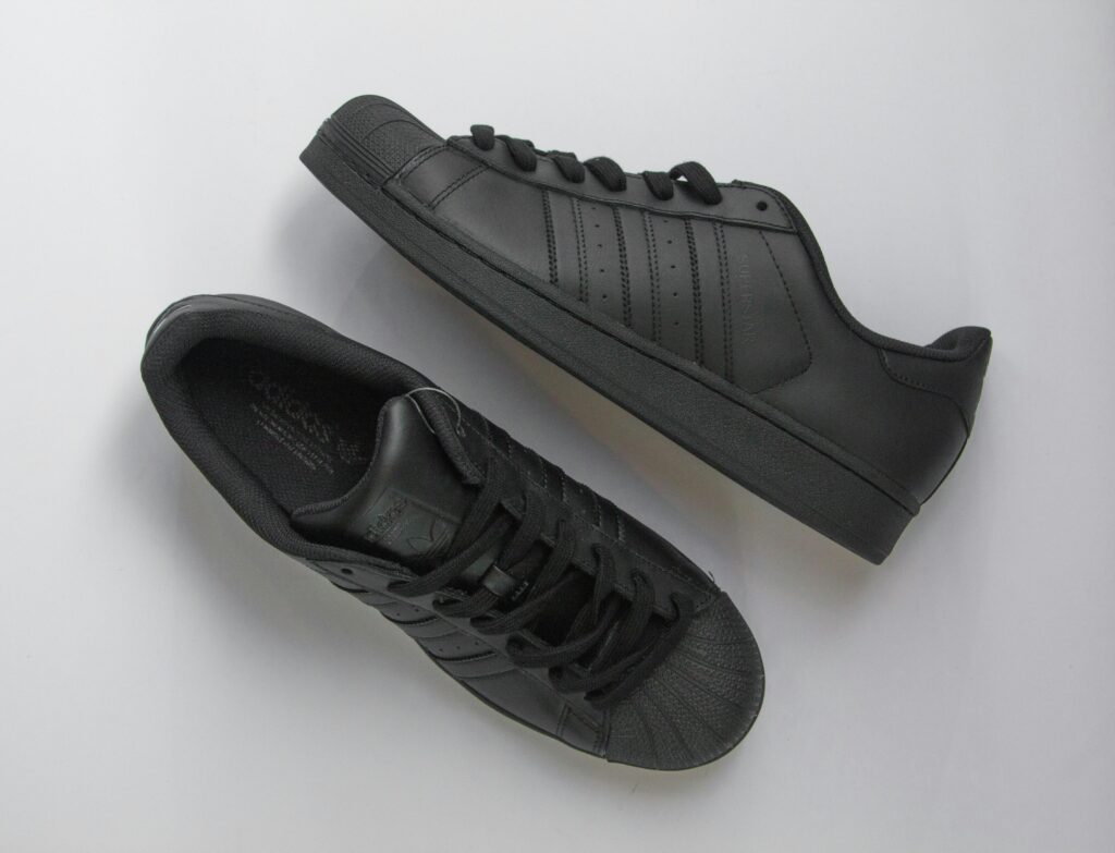 Elegant black sneakers on gray surface, showcasing a modern fashion style.