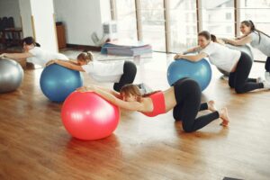 Women practicing fitness with exercise balls in a bright studio.