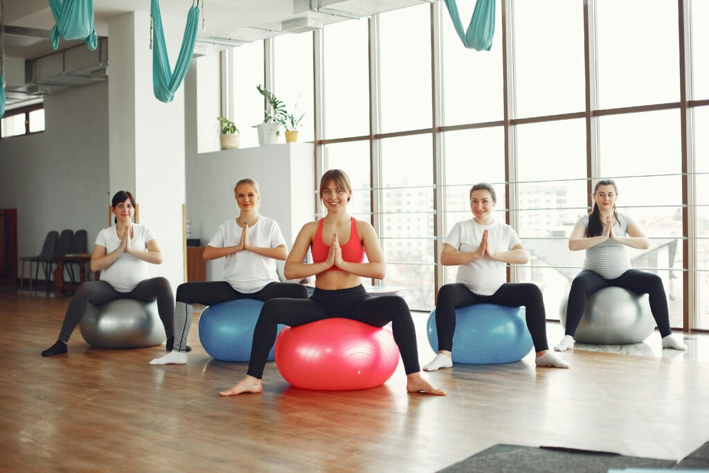 Pregnant women in a yoga class using exercise balls, promoting healthy lifestyle.