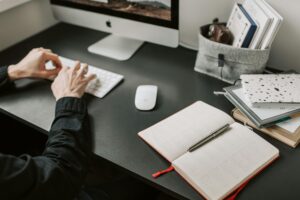 A cozy indoor workspace setup with a computer, keyboard, and notebooks, ideal for remote work.