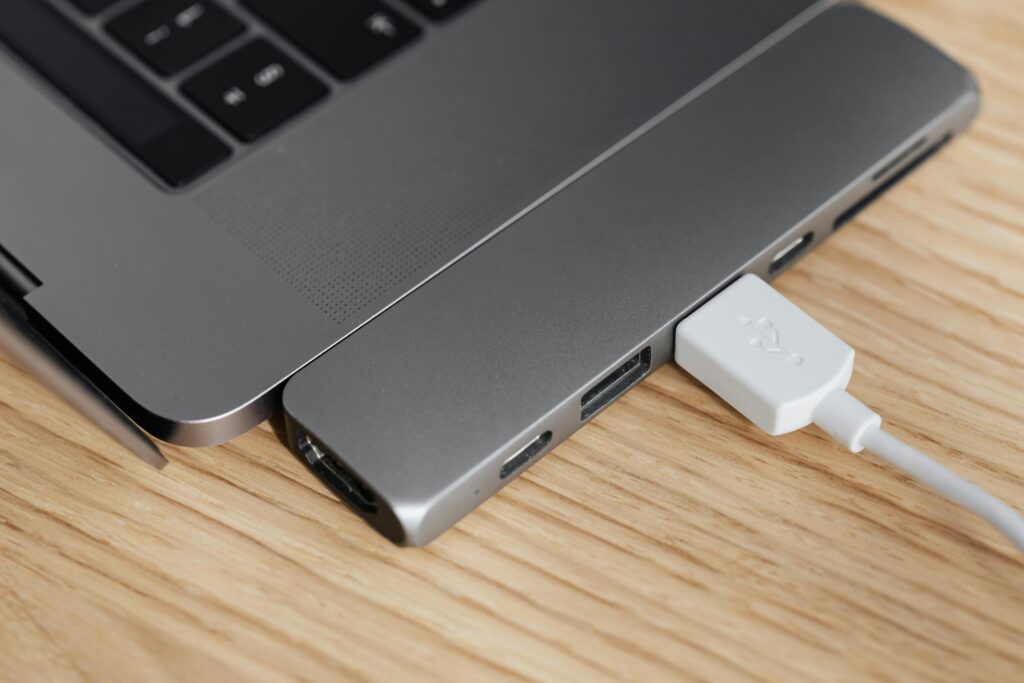 A multiport adapter connected to a laptop on a wooden desk, showcasing modern tech connectivity.