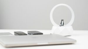 Modern workspace showcasing a sleek laptop, electronics, and minimalist decor with a cat-themed lamp.