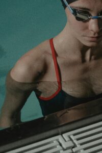 Close-up of a focused female swimmer at the poolside. Ready for a swim.
