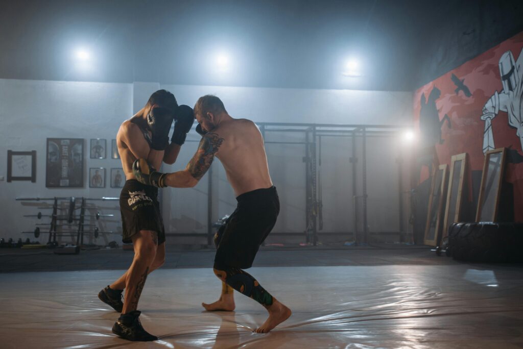 Two male MMA fighters sparring intensely in a gym setting.