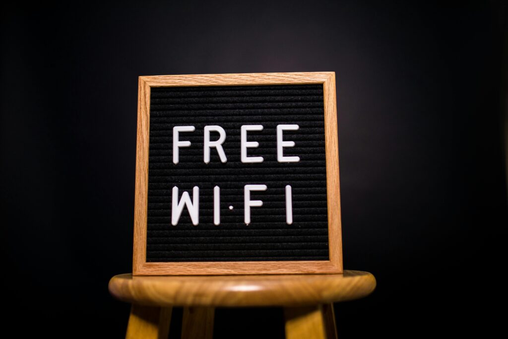 A wooden frame sign with 'Free Wi-Fi' text displayed on a stool in a dark room.