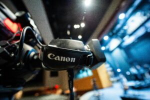 From below closeup of contemporary professional video camera with lens and handle placed near stage in studio