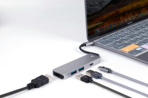 Close-up view of a USB hub connected to a laptop, showcasing various ports and cables on a white surface.