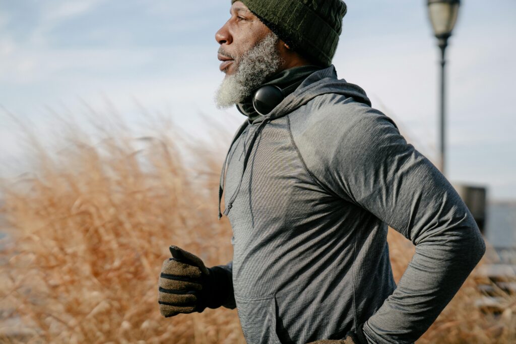 Senior African American man enjoying a run outdoors in warm autumn clothing.