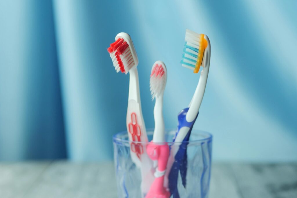 A trio of vibrant toothbrushes in a glass on a blue background, emphasizing dental hygiene.