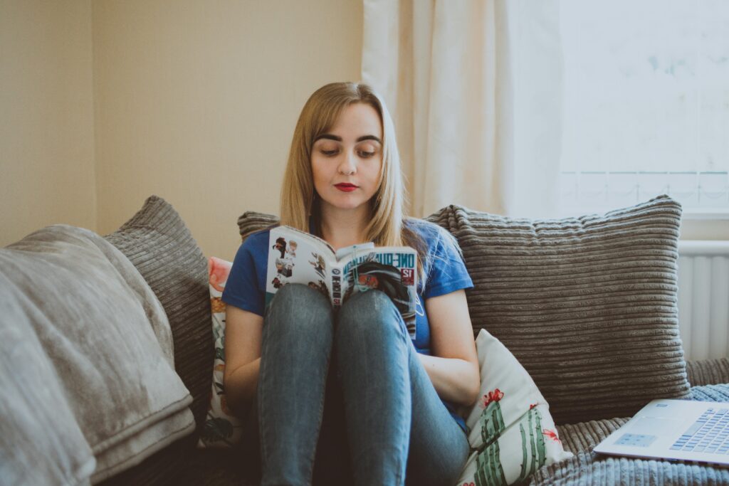 A woman enjoys reading manga while sitting comfortably on a cozy sofa, creating a relaxing atmosphere.