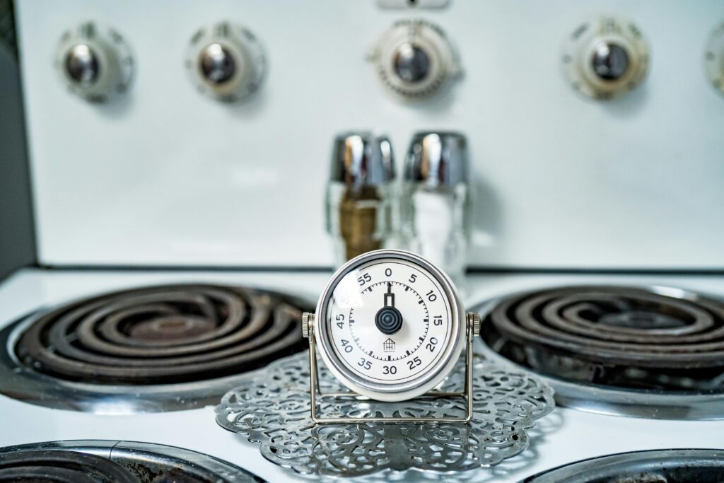 Close-up of a classic analog kitchen timer on a vintage gas stove, perfect for cooking themes.