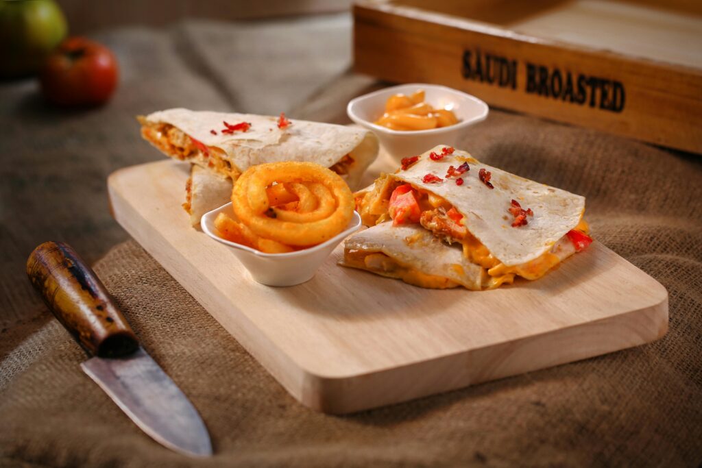 Tasty quesadilla with curly fries on a wooden board, perfect for a savory meal.