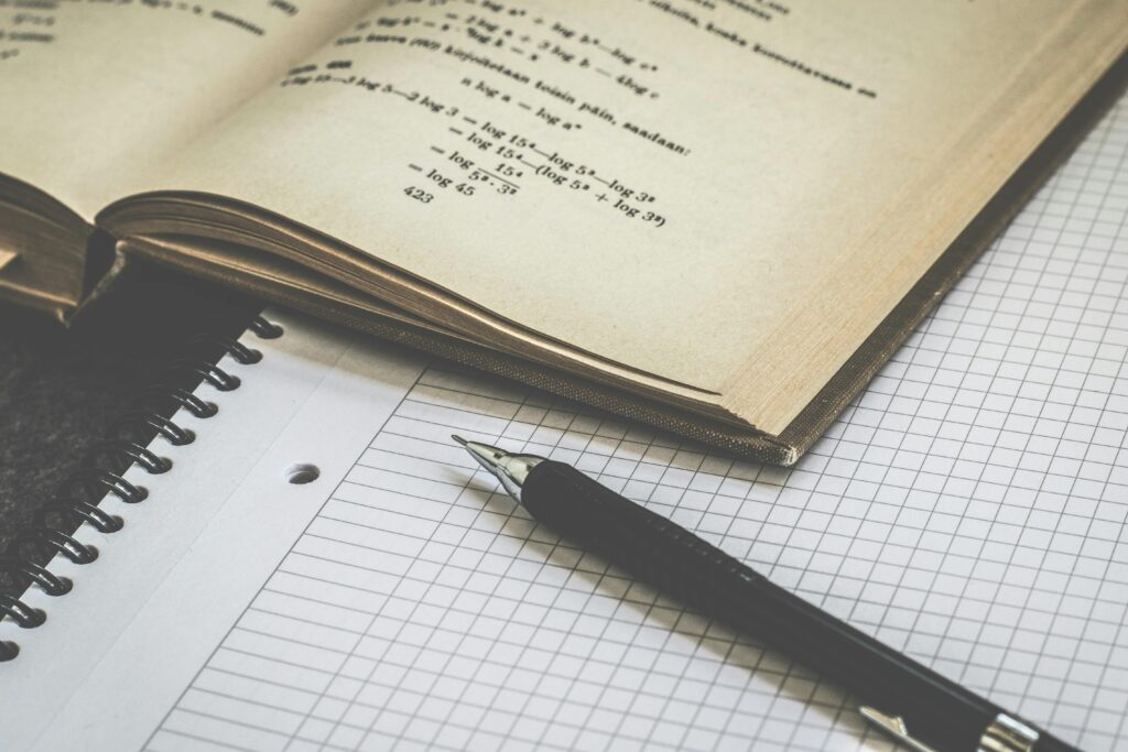 Mathematical study scene with open book, graph paper, and pen for learning and homework.