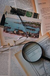 A nostalgic still life of vintage postcards, a map, eyeglasses, and a magnifying glass.