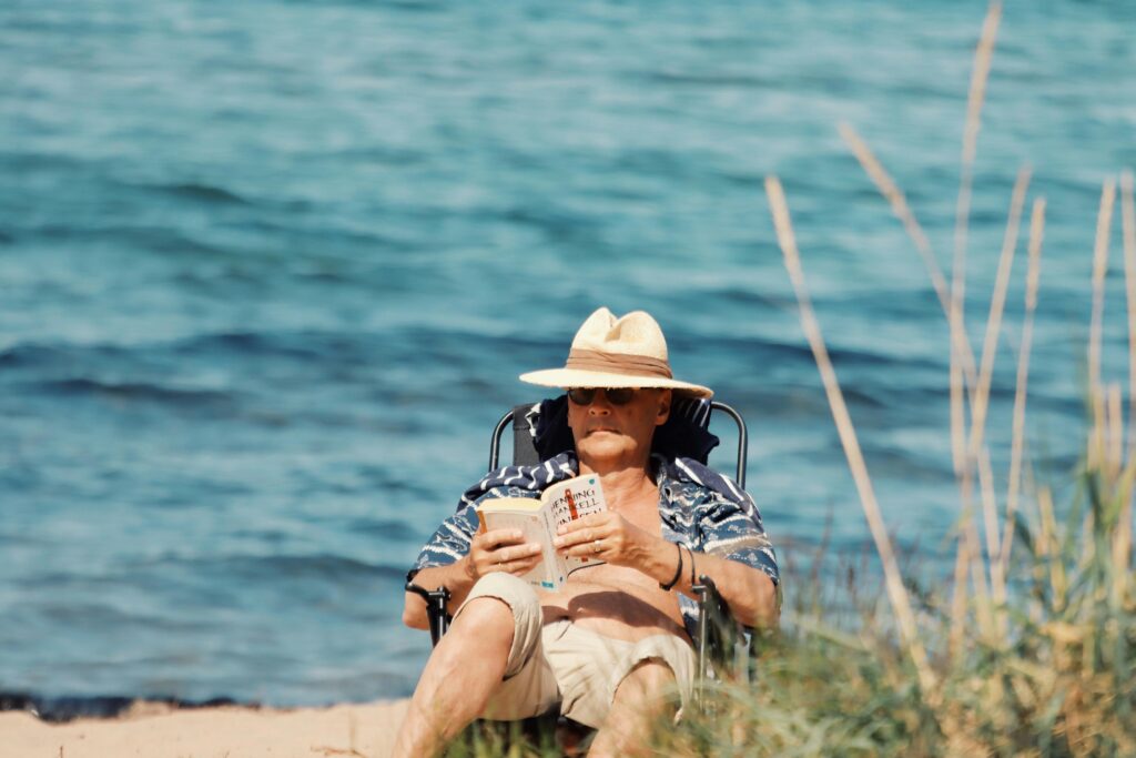Senior man enjoying a sunny day reading at Jönköping beach in Sweden.
