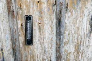 A vintage thermometer mounted on a rustic wooden wall. Perfect for themes of nostalgia and weather monitoring.