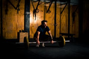 A man prepares to lift a barbell in a dimly lit gym environment, focusing on strength training.