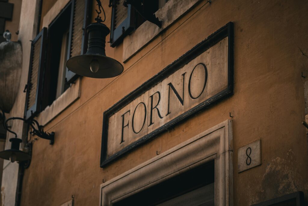 Vintage sign indicating a bakery ('Forno') in the historic streets of Rome, Italy.