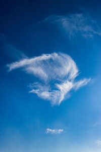 Capture the serenity of nature with wispy clouds against a clear blue sky.