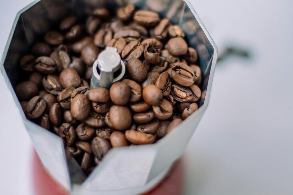 High-angle view of fresh coffee beans in a Moka pot, ideal for brewing espresso at home.