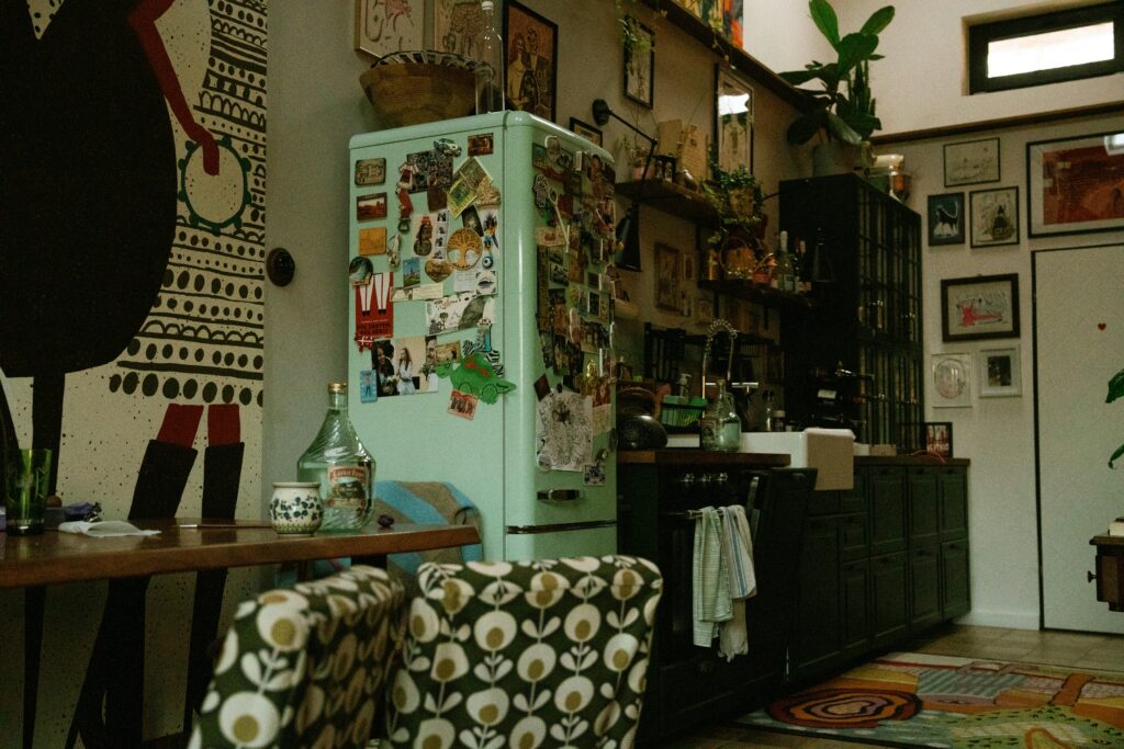 Stylish kitchen interior featuring retro fridge, vibrant art, and cozy, eclectic design elements.