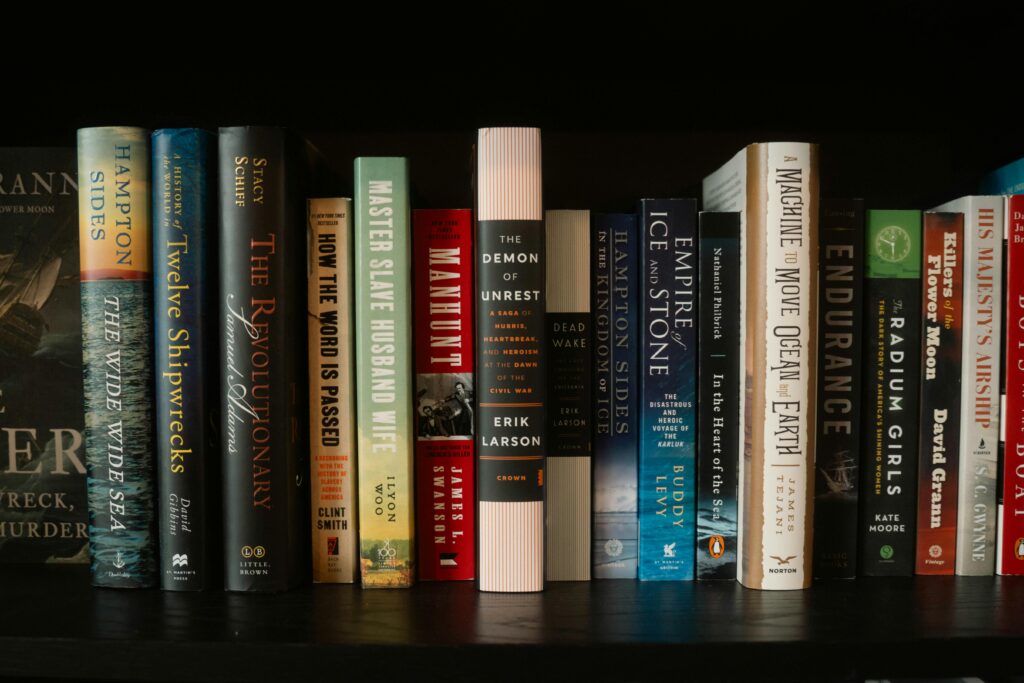 An array of colorful books lined up on a bookshelf with diverse themes and authors.