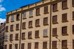 Exterior view of a building with closed shutters on all windows under a clear sky.