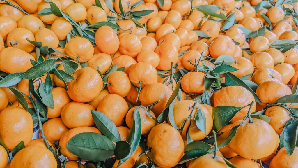 Pile of organic oranges in the market stall. Fruit orange background. Closeup of Chinese oranges in a grocery store
