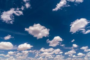 An expansive view of a sunny blue sky filled with fluffy white clouds, perfect for serene and nature-themed projects.