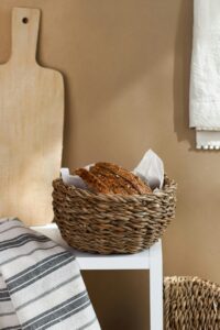 Freshly baked bread in a wicker basket on a kitchen counter with rustic decor.