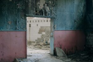 Explore the eerie beauty of decay in this abandoned building with peeling walls and debris.