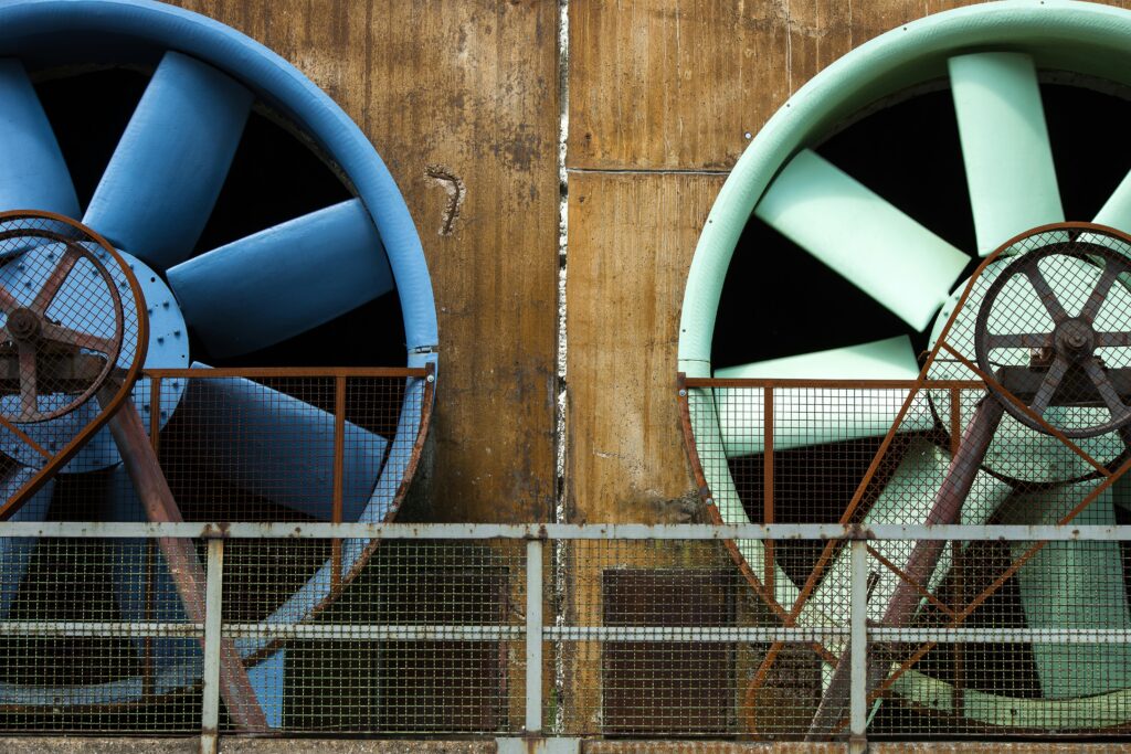 Close-up of large industrial ventilators mounted on an aging building exterior.