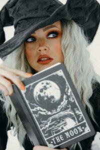 Mysterious witch in costume with tarot book, perfect for Halloween.