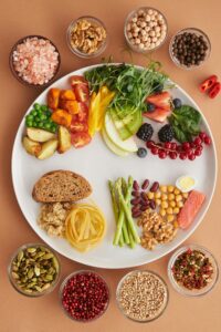 A vibrant assortment of healthy foods on a plate, showcasing a balanced diet with fruits, vegetables, nuts, and grains.