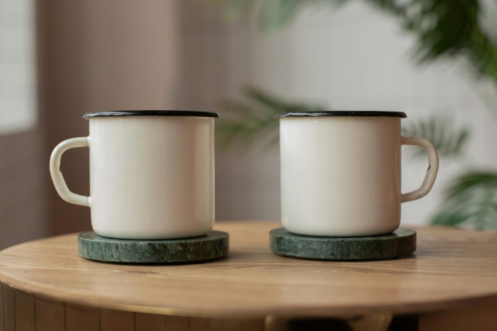 Two white ceramic mugs on marble coasters, perfect for a modern kitchen setting.