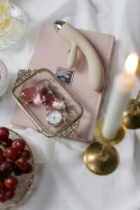 An elegant display of romantic accessories including a book, candles, and grapes.
