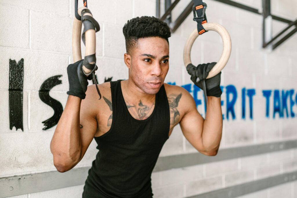 A determined athlete strength-training on gymnastic rings at an indoor gym, emphasizing fitness and focus.
