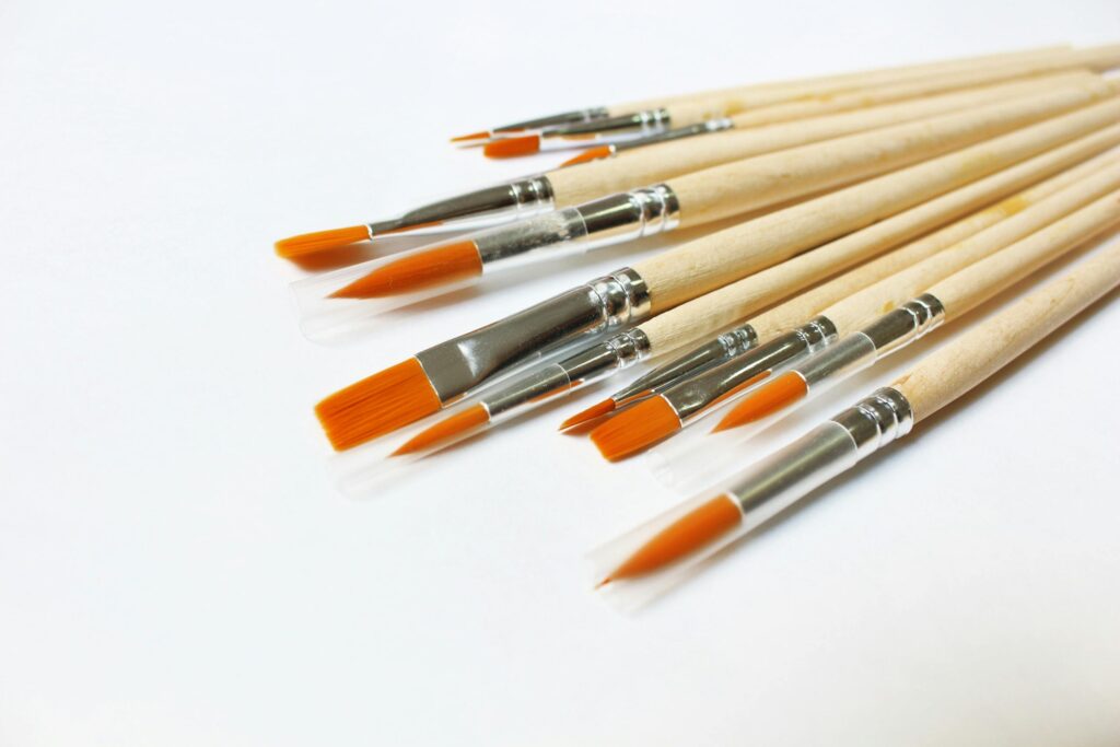A set of wooden-handle paintbrushes with orange bristles arranged on a white background.