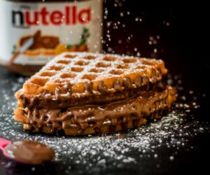 Delicious waffles with creamy chocolate hazelnut spread, topped with sugar dusting.