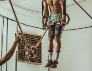 Focused athlete engages in a crossfit workout using gym rings indoors, showcasing strength and determination.