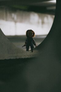 Eerie doll figure standing alone in a dimly lit tunnel, creating a horror ambiance.