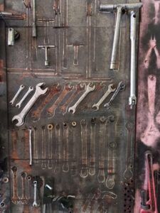 A variety of wrenches organized on a rustic tool board in a workshop setting.