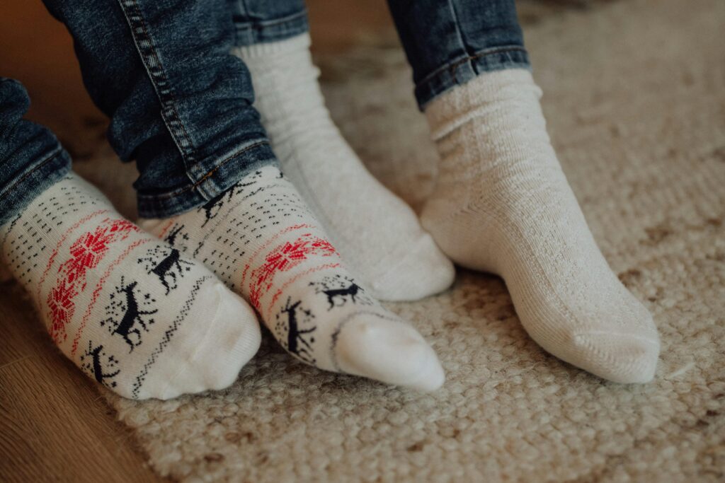 Two people wearing festive socks on a cozy carpet floor indoors.