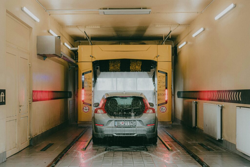 A modern car undergoing an automated interior car wash with bright lights and soapy water.