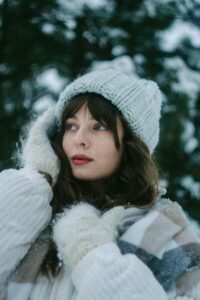 Young woman in warm winter attire amidst snow-covered scenery, embodying the essence of winter warmth and style.
