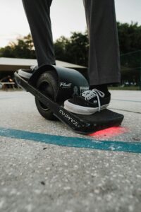A person riding an electric skateboard outdoors on a concrete surface.