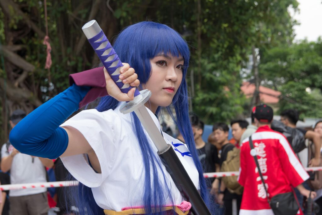 Cosplay participant dressed as a character holding a sword at an outdoor event.