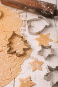 Christmas cookie cutters on dough with rolling pin. Perfect for holiday baking.