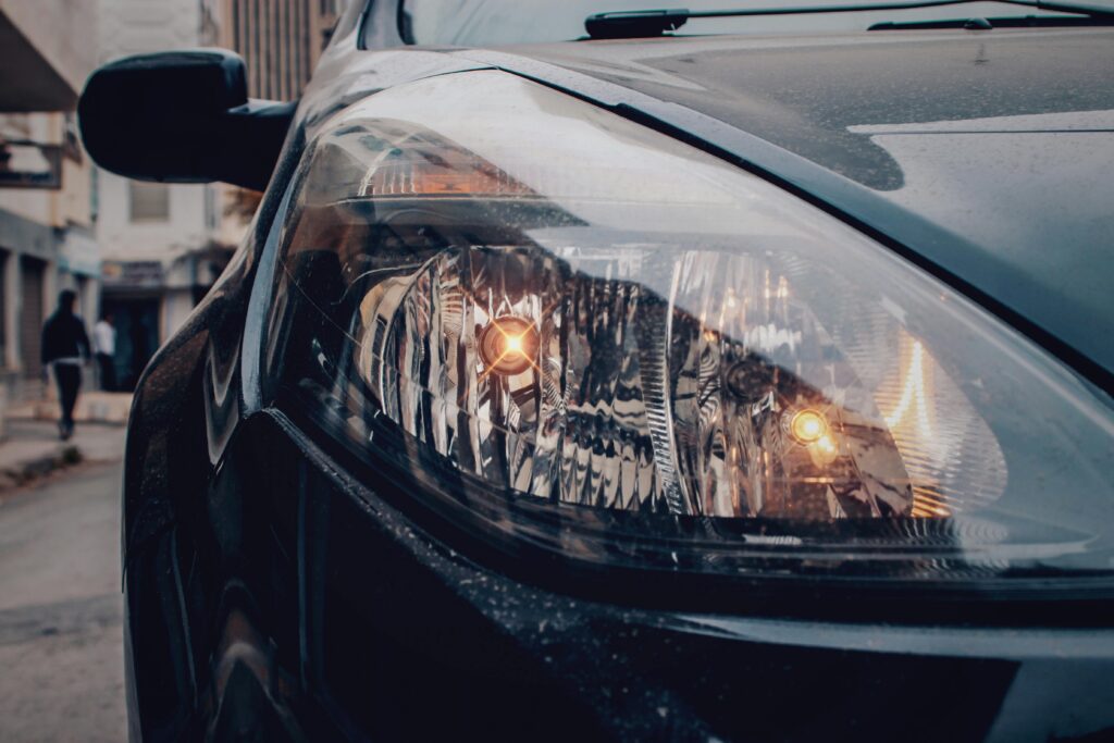 Detailed close-up of a car's headlight on a city street, showcasing urban automotive details.