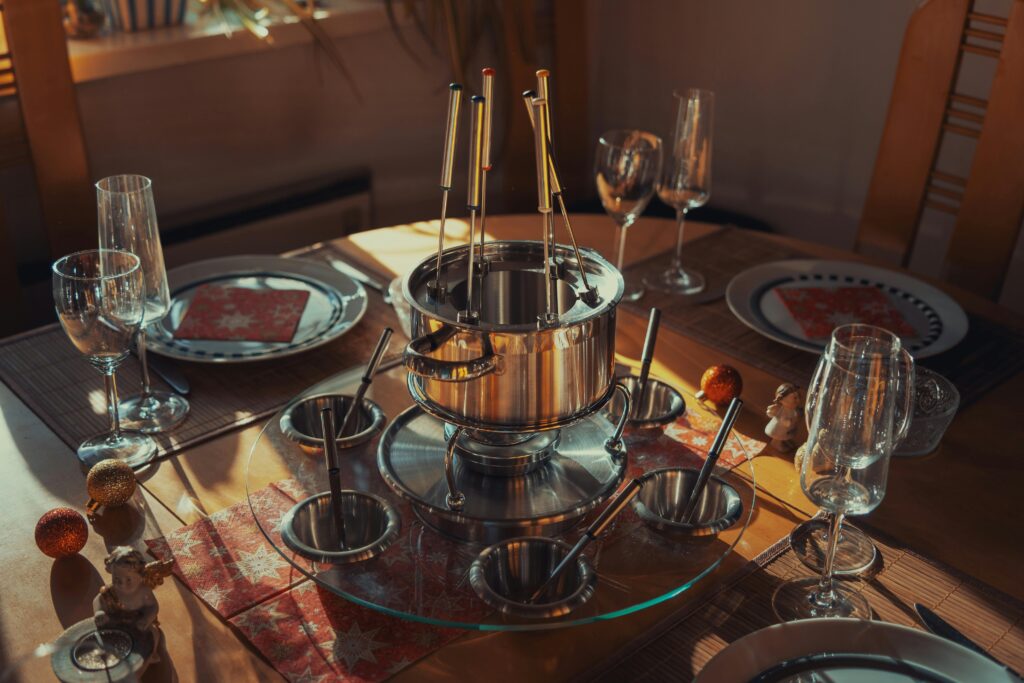 A beautifully set table with a fondue pot, glassware, and decorative setup, perfect for dining occasions.